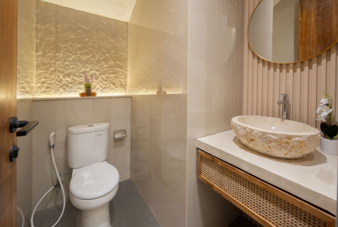 Modern bathroom with textured stone wall, vessel sink, and warm lighting in a Bali leasehold villa