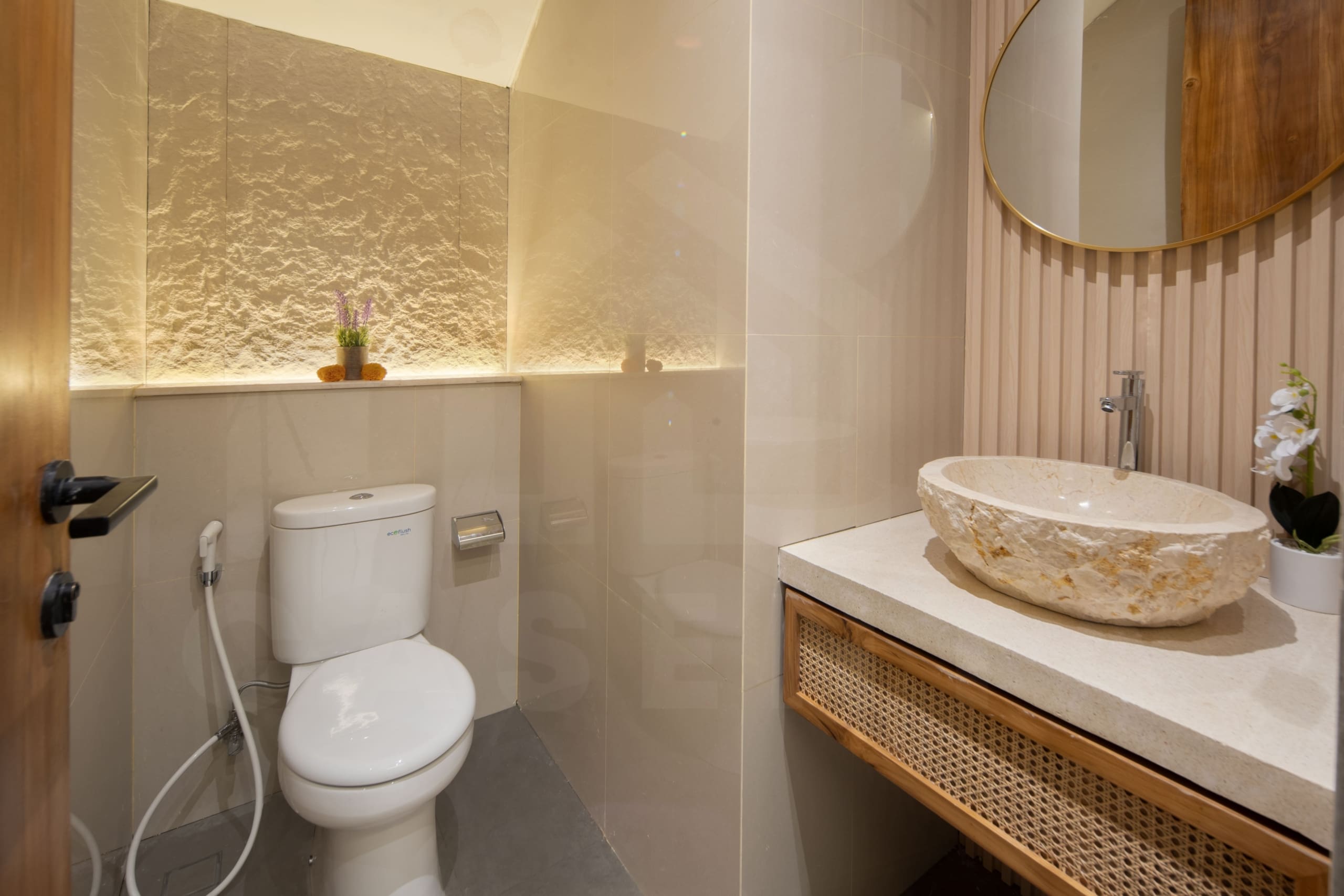 Modern bathroom with textured stone wall, vessel sink, and warm lighting in a Bali leasehold villa