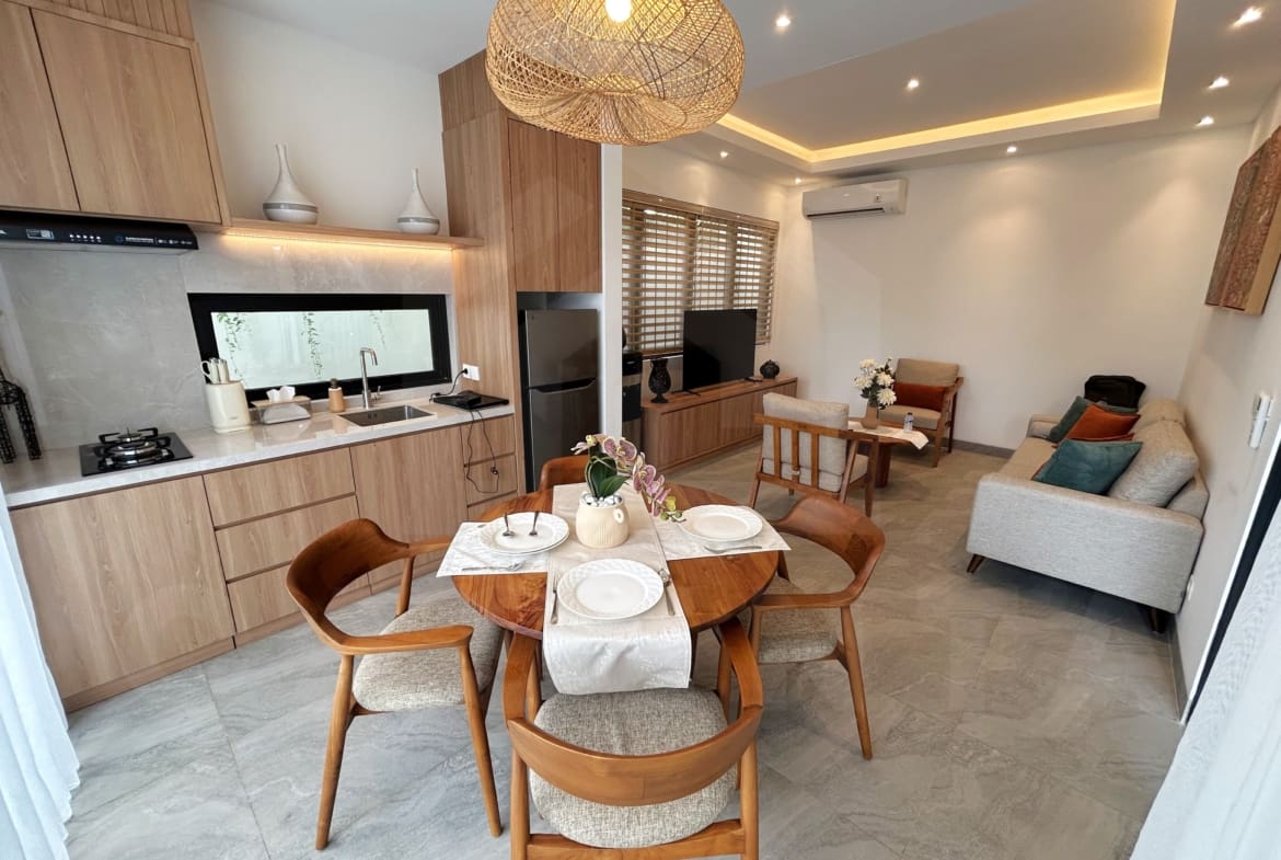 Open-plan dining and living area with wood kitchen, cozy seating, and warm lighting.