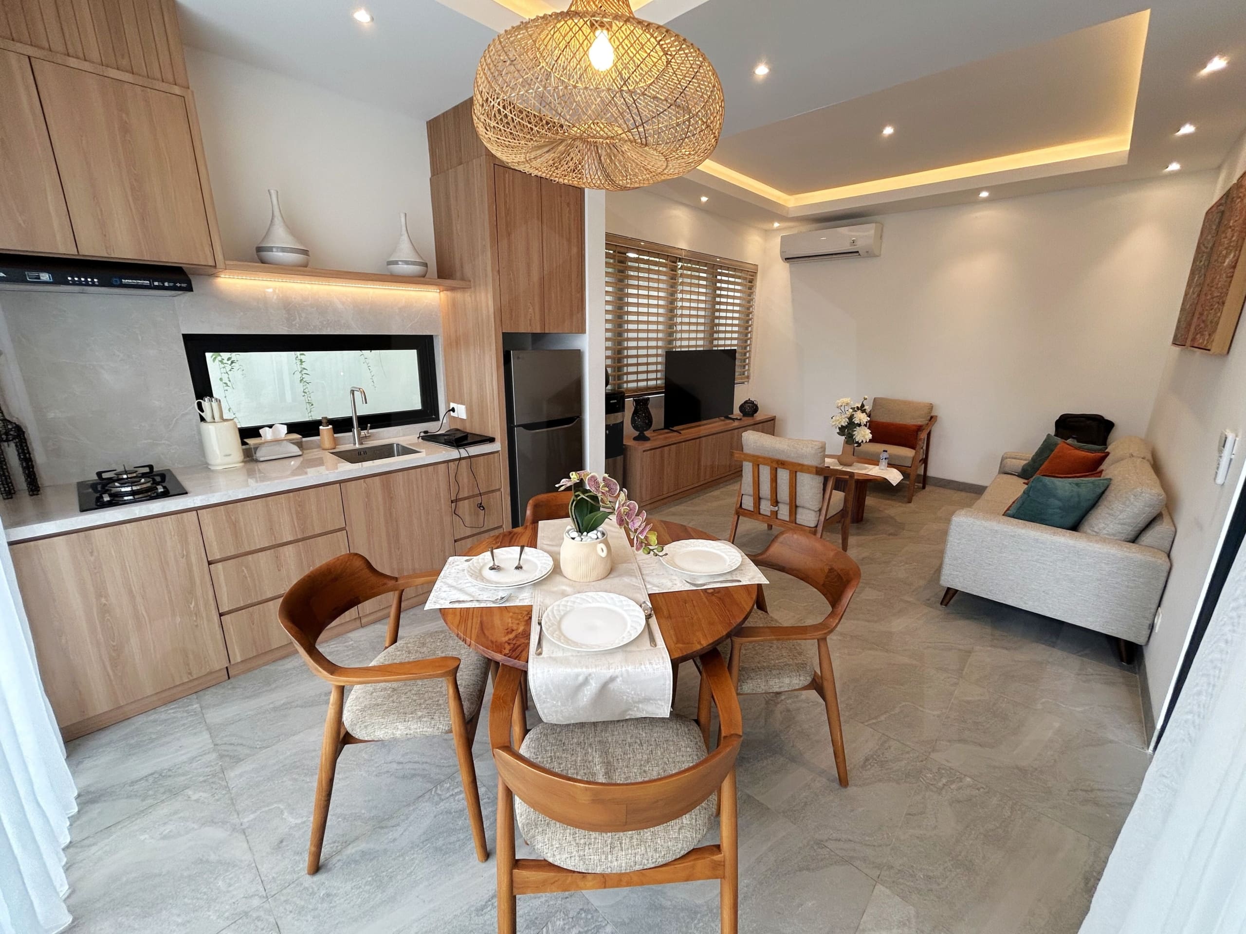 Open-plan dining and living area with wood kitchen, cozy seating, and warm lighting.