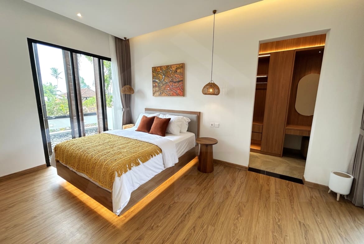Spacious villa bedroom with balcony doors, warm lighting, and walk-in wardrobe.