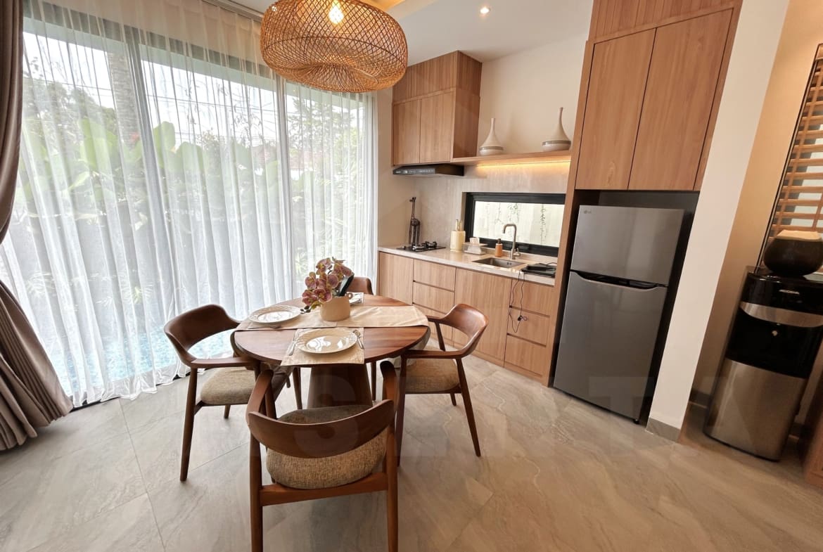 Modern villa kitchen and dining area with wood cabinetry, round table, and large windows facing the pool.