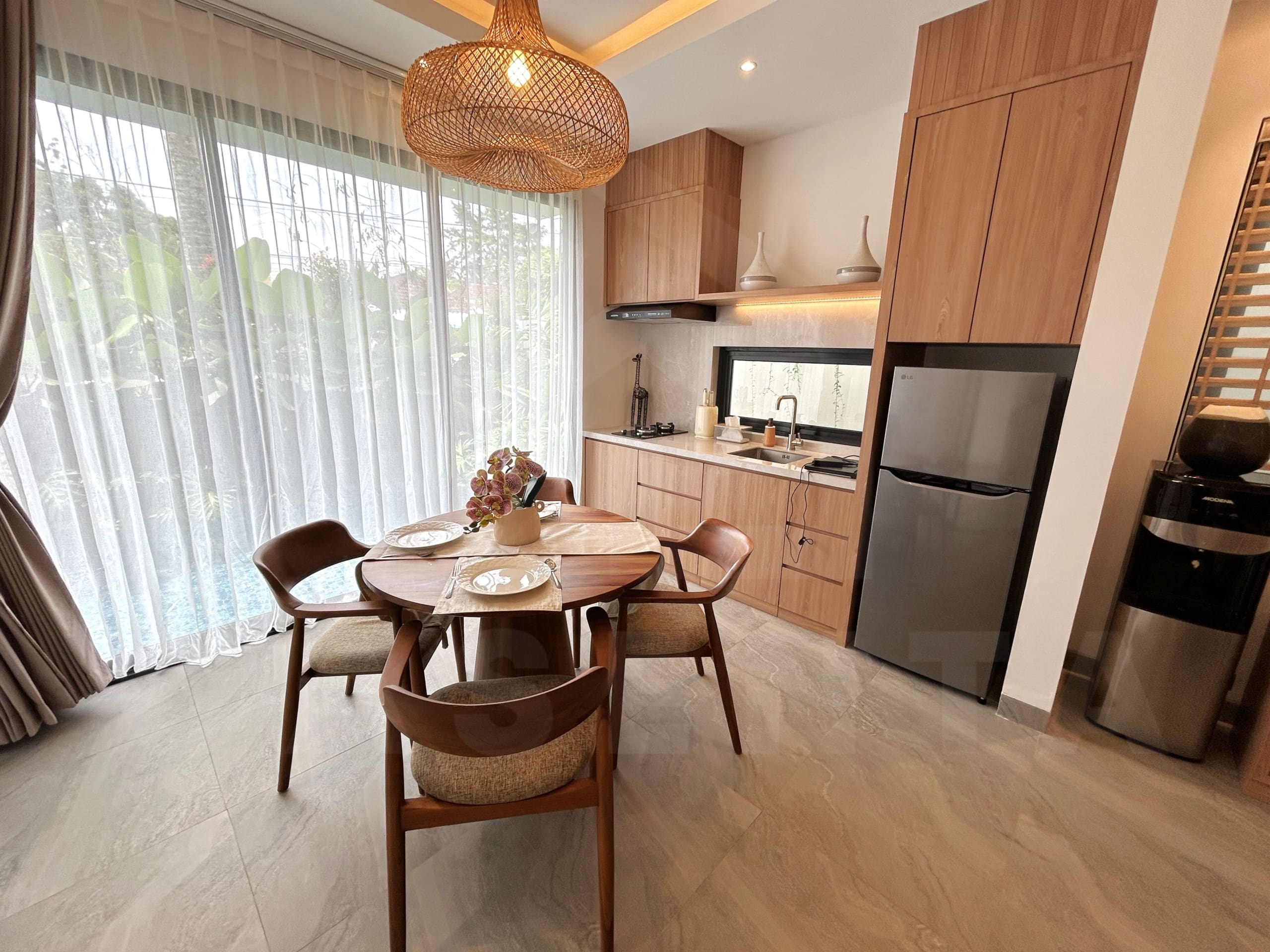 Modern villa kitchen and dining area with wood cabinetry, round table, and large windows facing the pool.