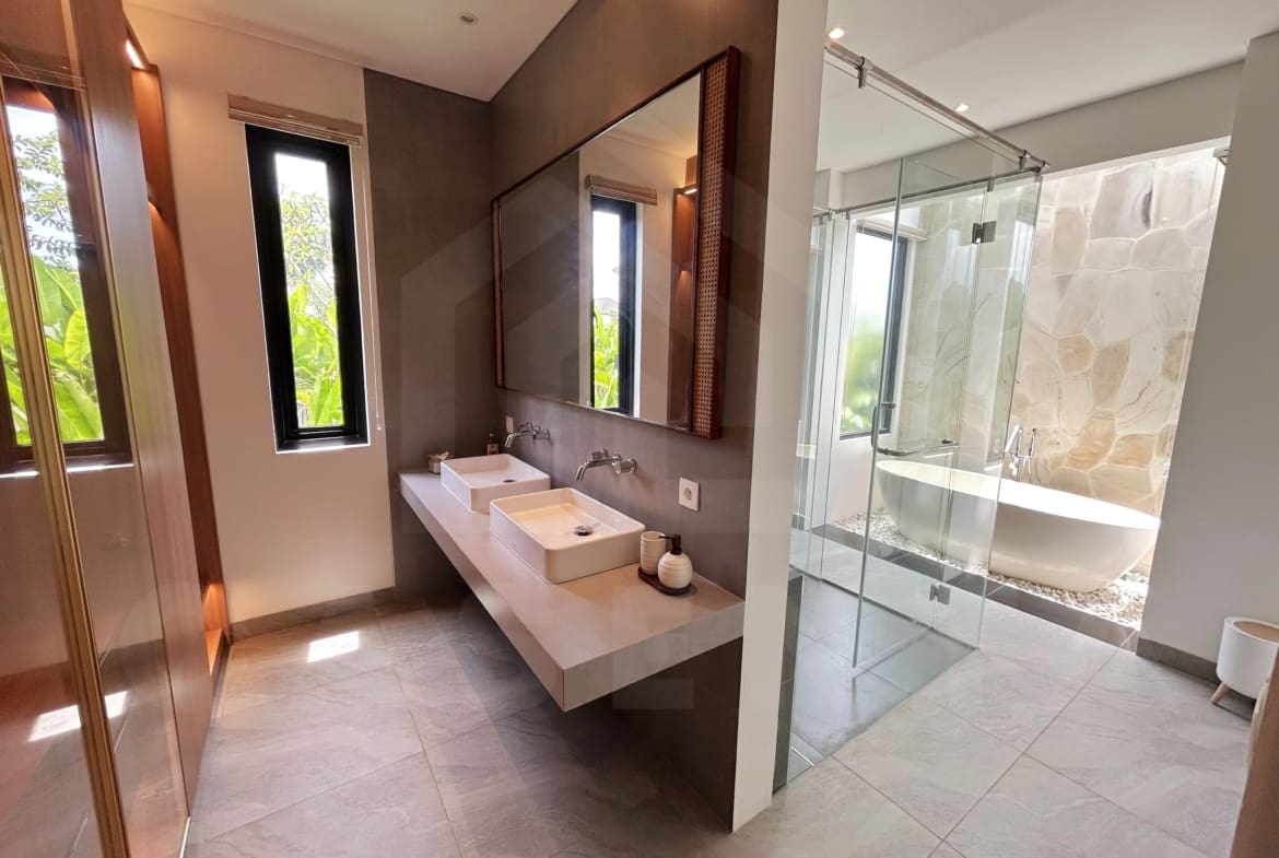 Elegant villa bathroom with double vanity, glass shower, and stone-wall bathtub area