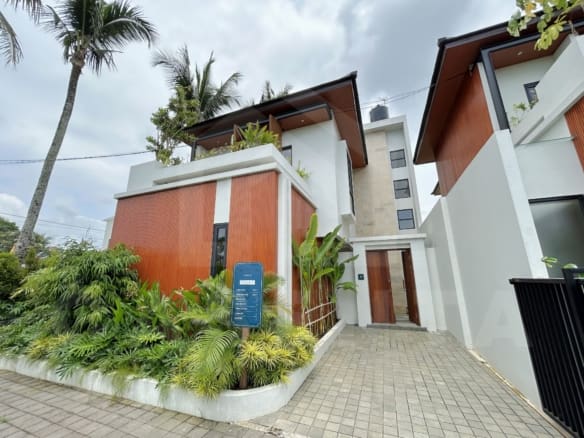 Contemporary villa exterior with wood paneling, tropical landscaping, and private entrance.
