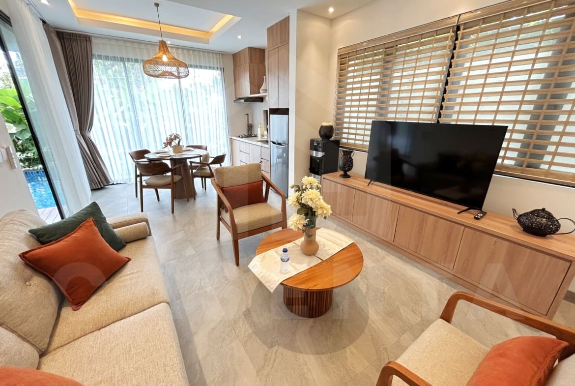 Bright living and dining area with wood furniture, large windows, and poolside views.