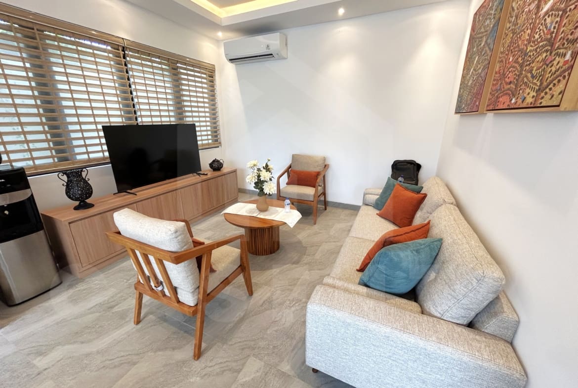 Cozy villa living room with neutral sofa, wood furniture, and large TV console.