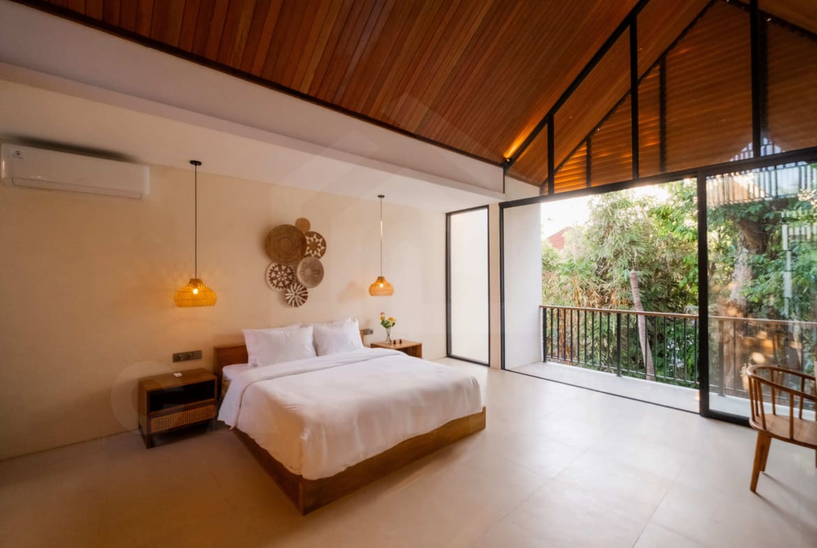 Bedroom opening to balcony surrounded by trees