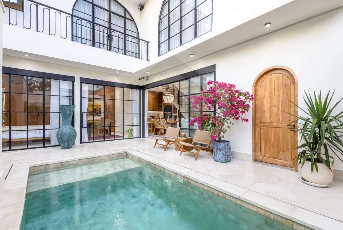 Balangan villa outdoor lounge with rattan chairs and flowering plants by the pool