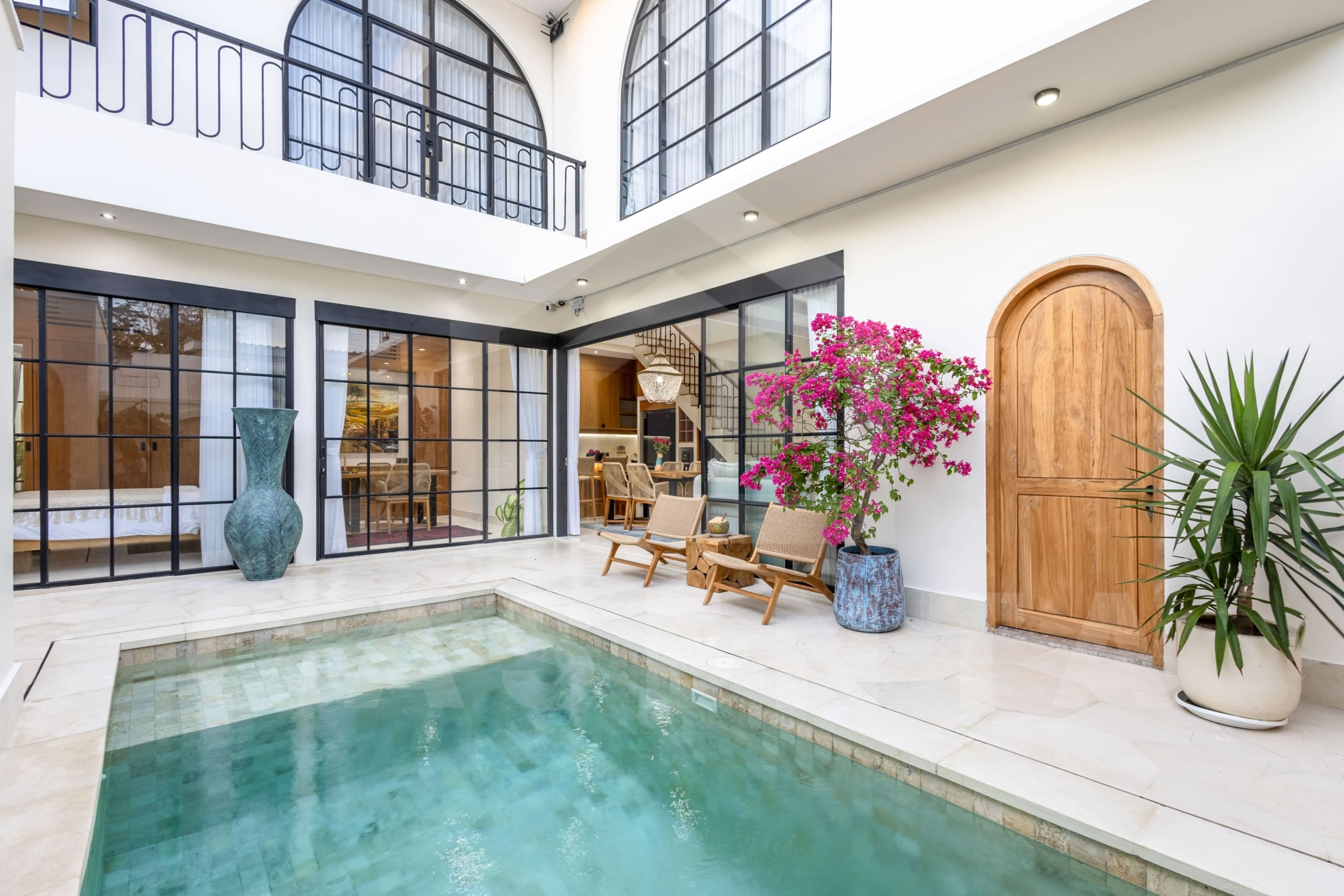 Balangan villa outdoor lounge with rattan chairs and flowering plants by the pool