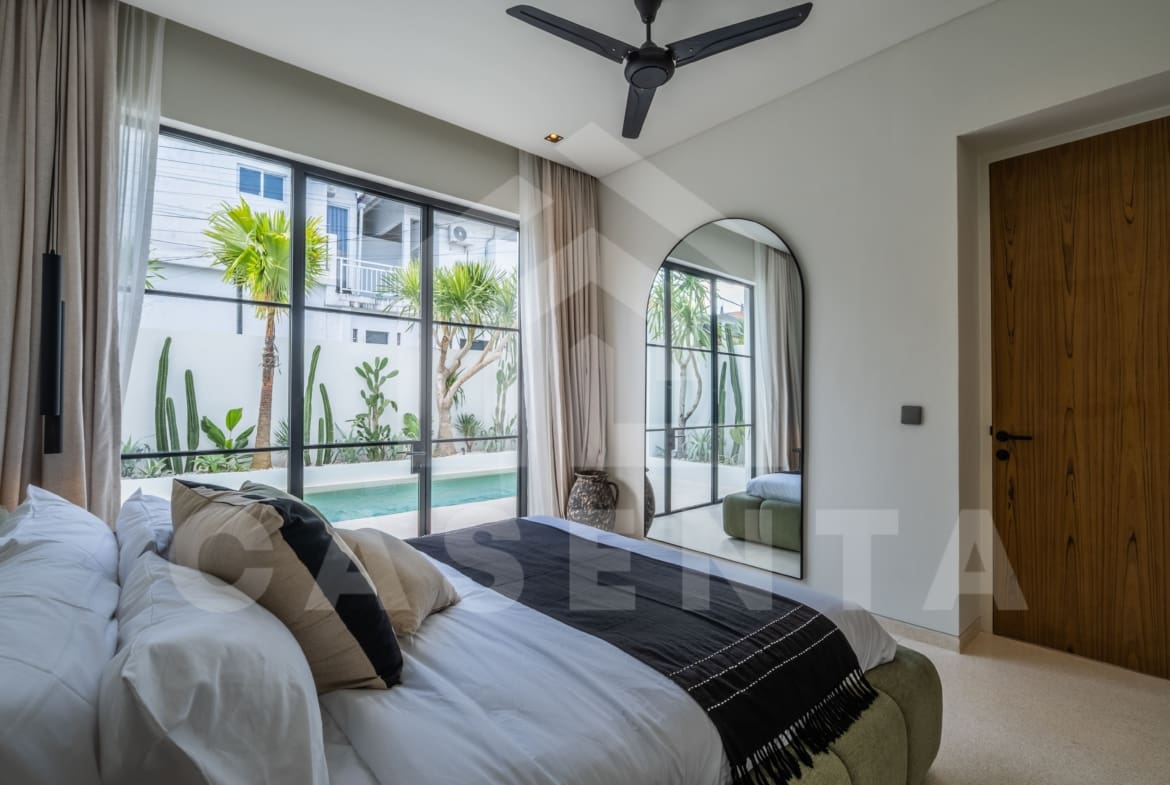 Bright ensuite bedroom with pool views through full-height glass windows and minimalist décor