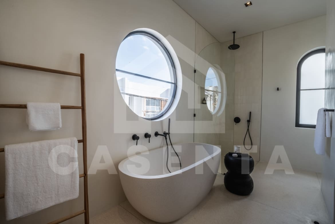 Contemporary bathroom with freestanding bathtub, circular window, and walk-in shower