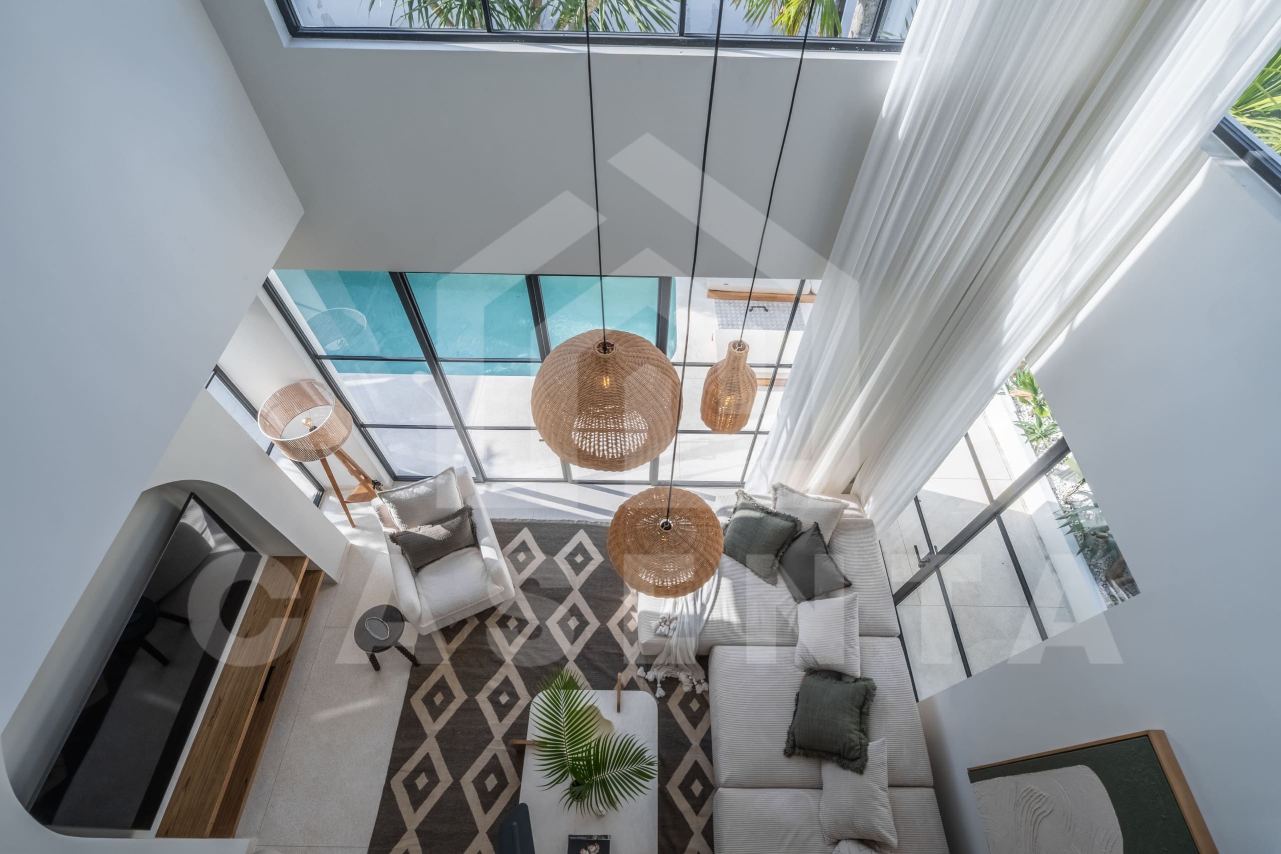 Double-height living room overlooking the pool with rattan pendant lights