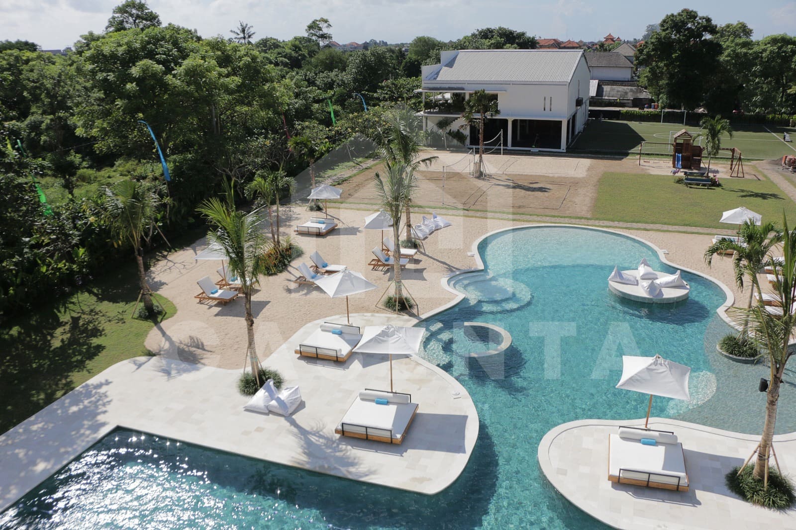 Aerial view of Jimbaran villa public pool courtyard with lagoon design and sun loungers