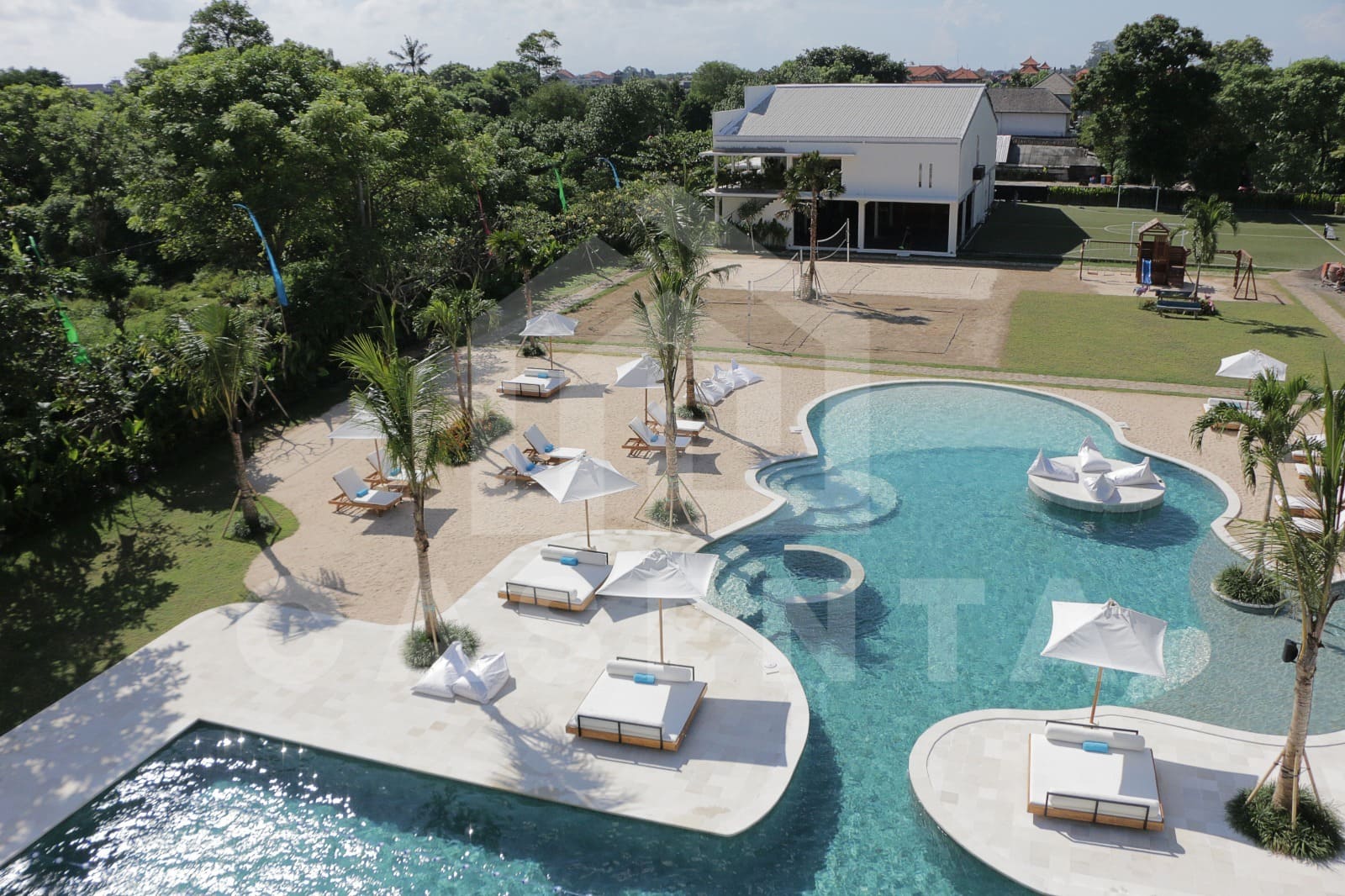 Aerial view of Jimbaran villa public pool courtyard with lagoon design and sun loungers