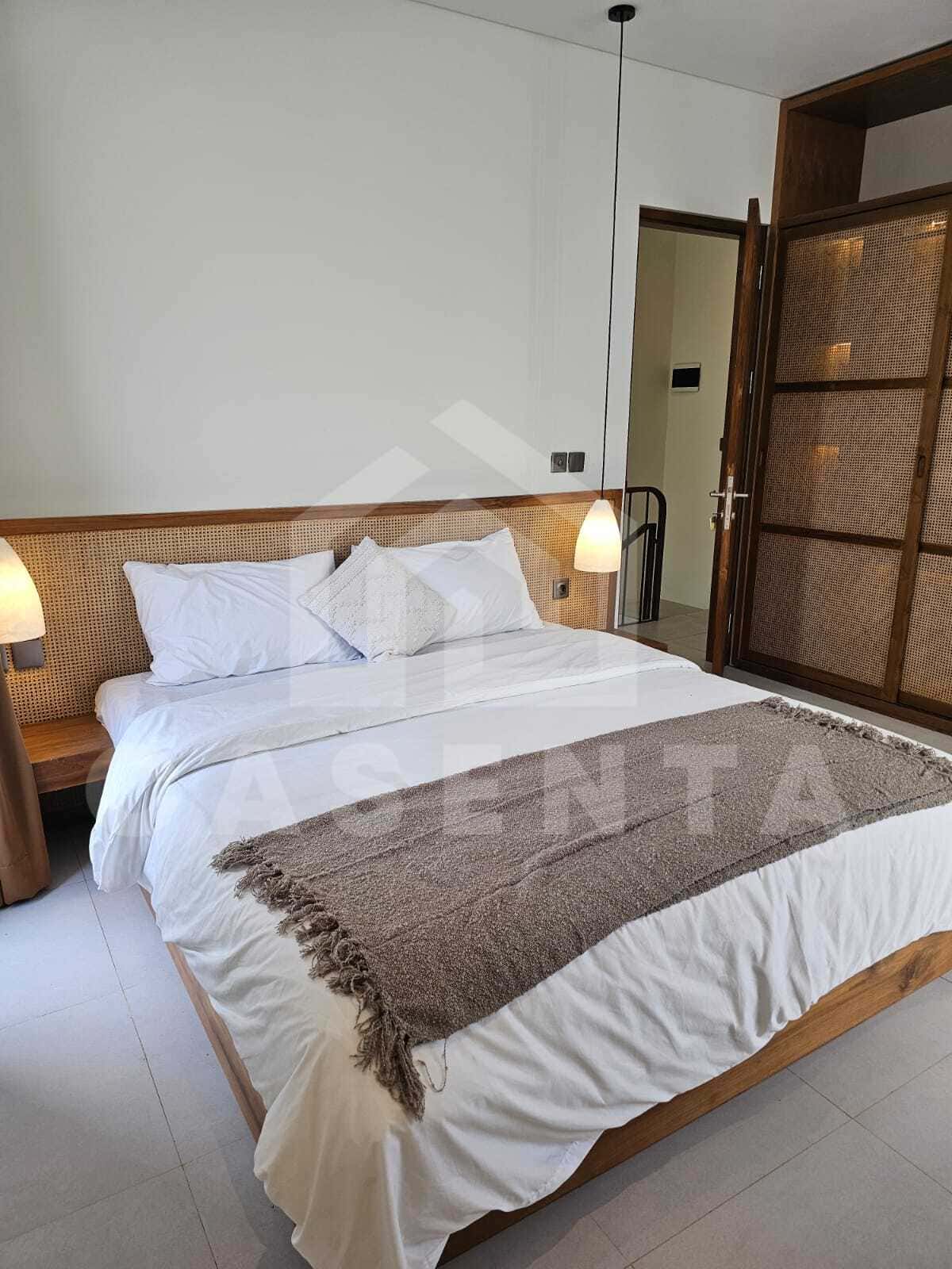 Ensuite bedroom with wooden furniture in cemagi villa