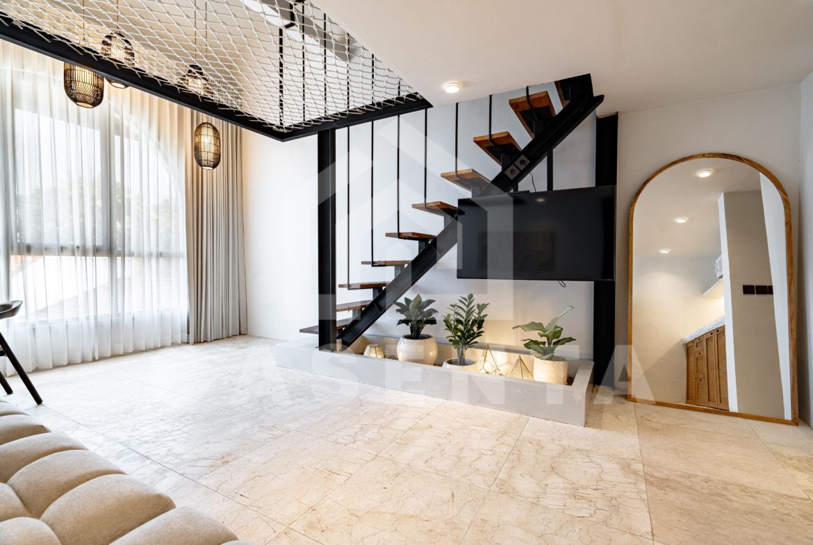 Double-height living room in Sanur apartment with floating staircase