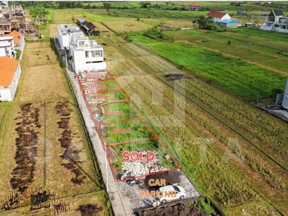 Cemagi land development plots with paved access road and rice field views