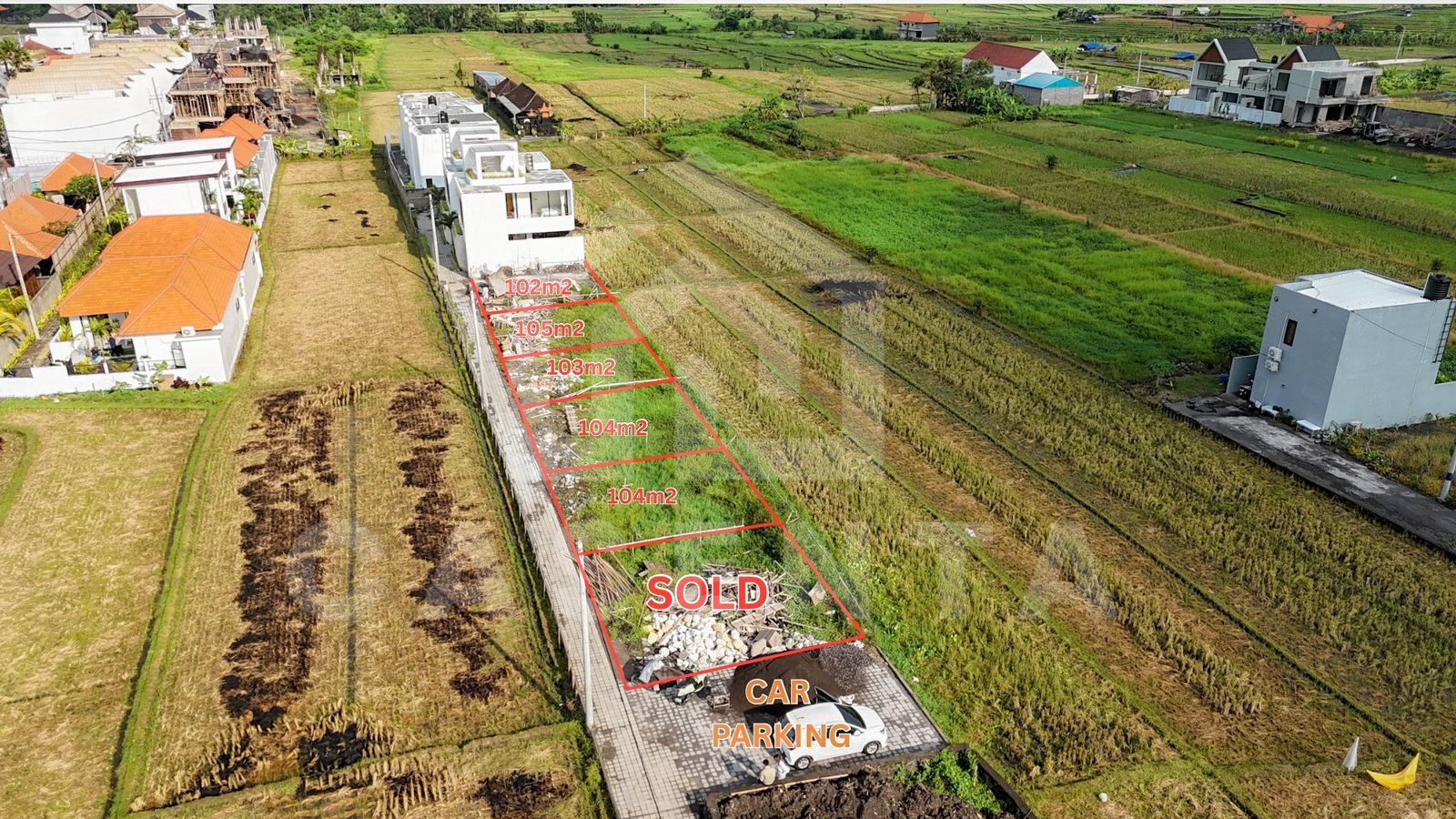 Cemagi land development plots with paved access road and rice field views