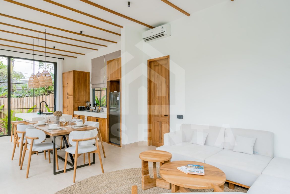 Bright living room and kitchen area in modern Ubud villa with natural wood finishes