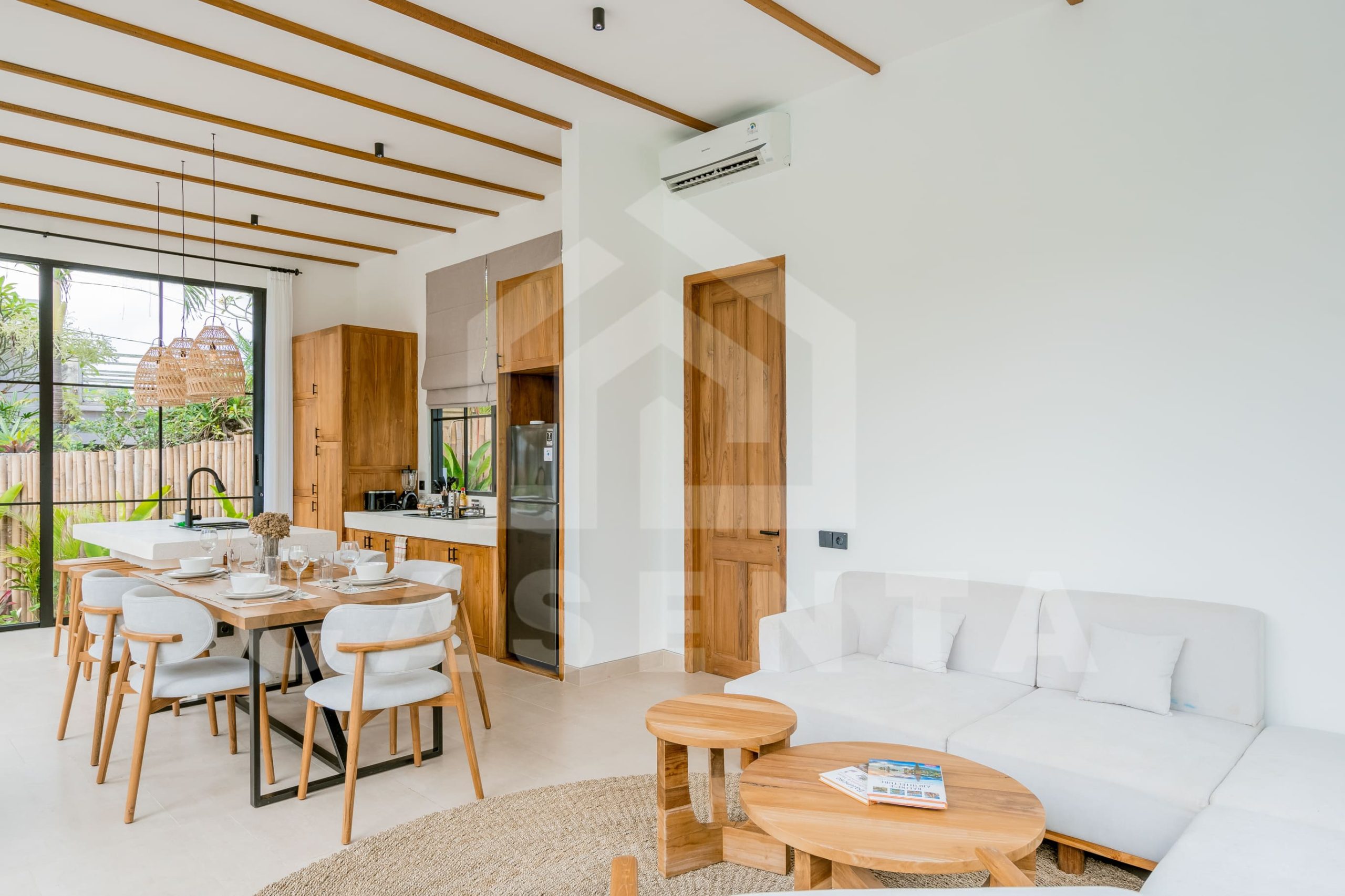 Bright living room and kitchen area in modern Ubud villa with natural wood finishes
