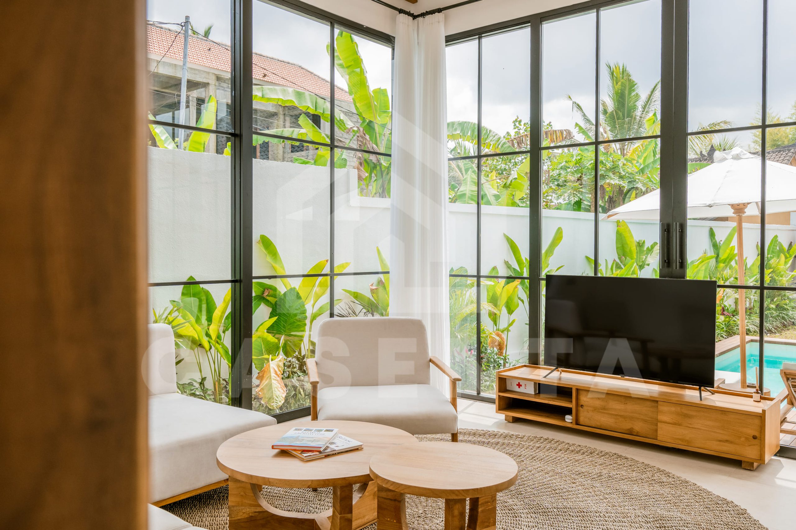 Spacious living area with large windows overlooking garden in Ubud villa