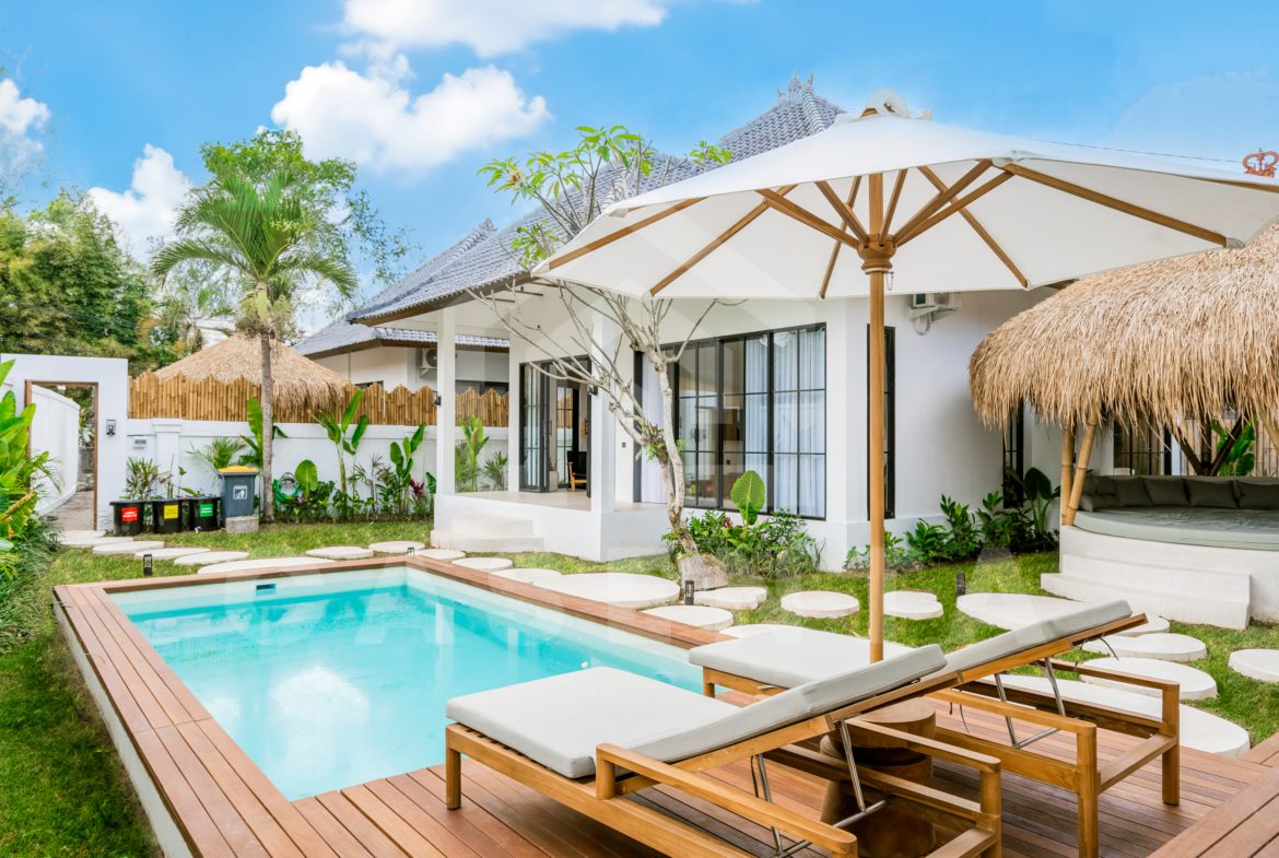 Pool deck with sun loungers and umbrella in Ubud villa