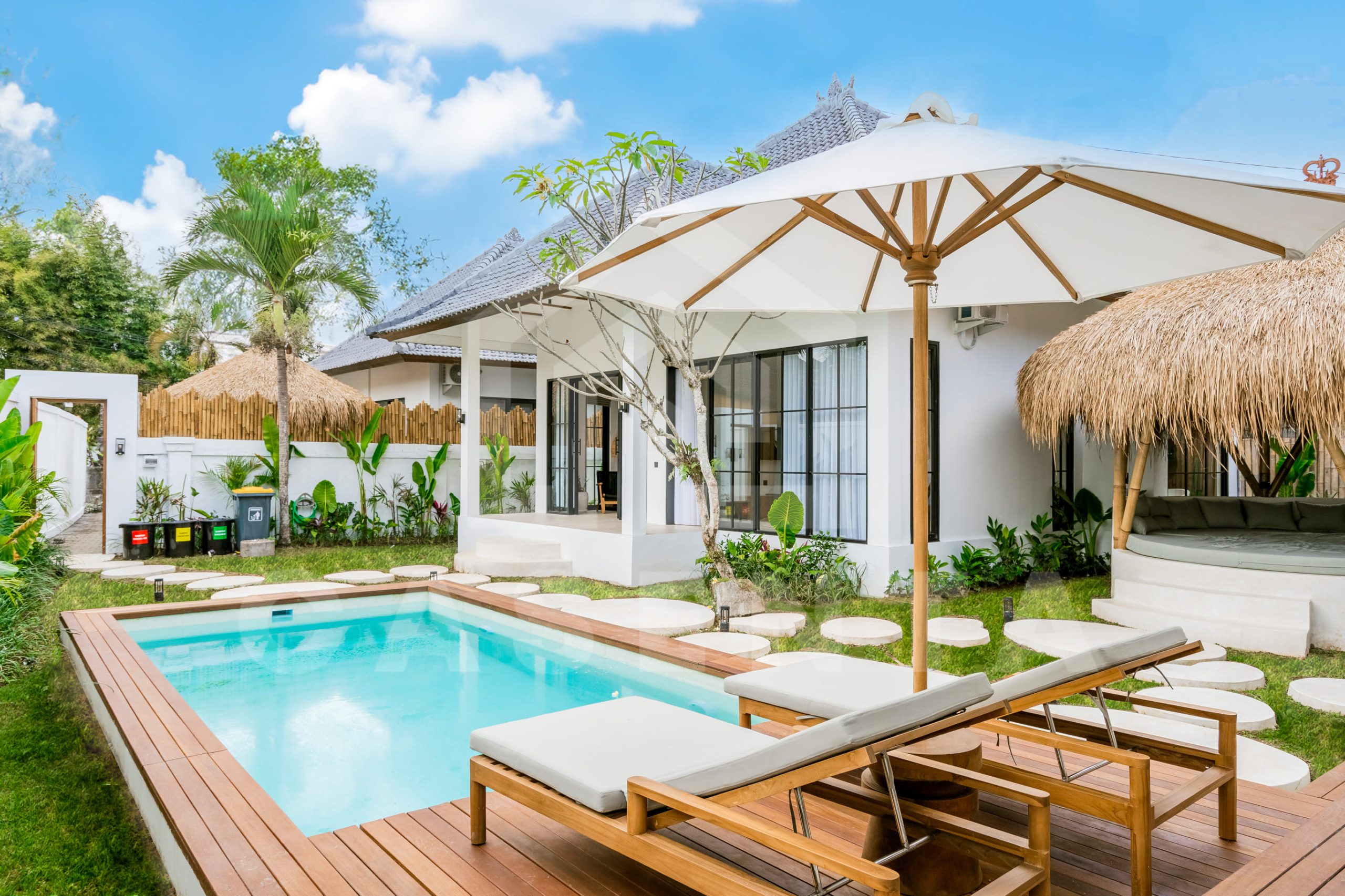 Pool deck with sun loungers and umbrella in Ubud villa