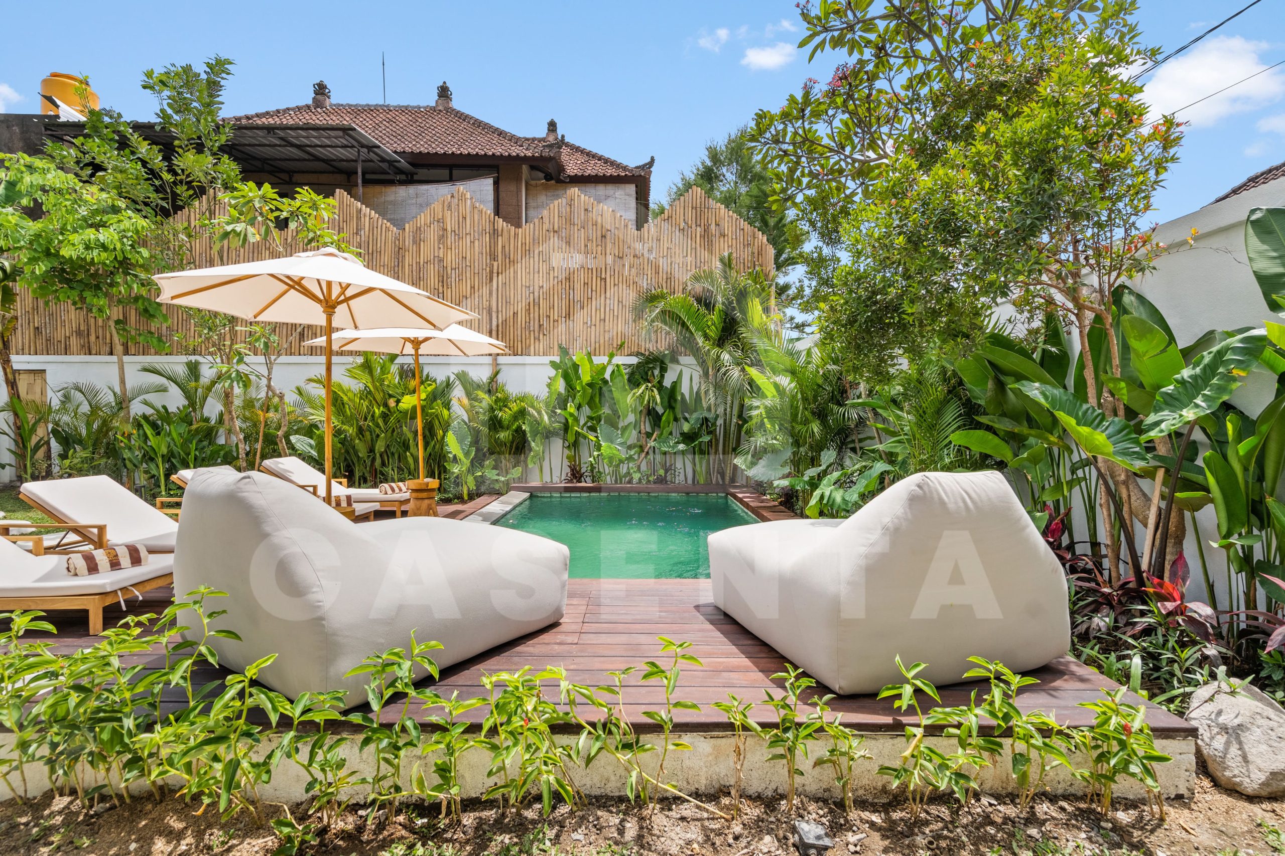 tropical garden and pool deck with lounge seating in Sayan villa